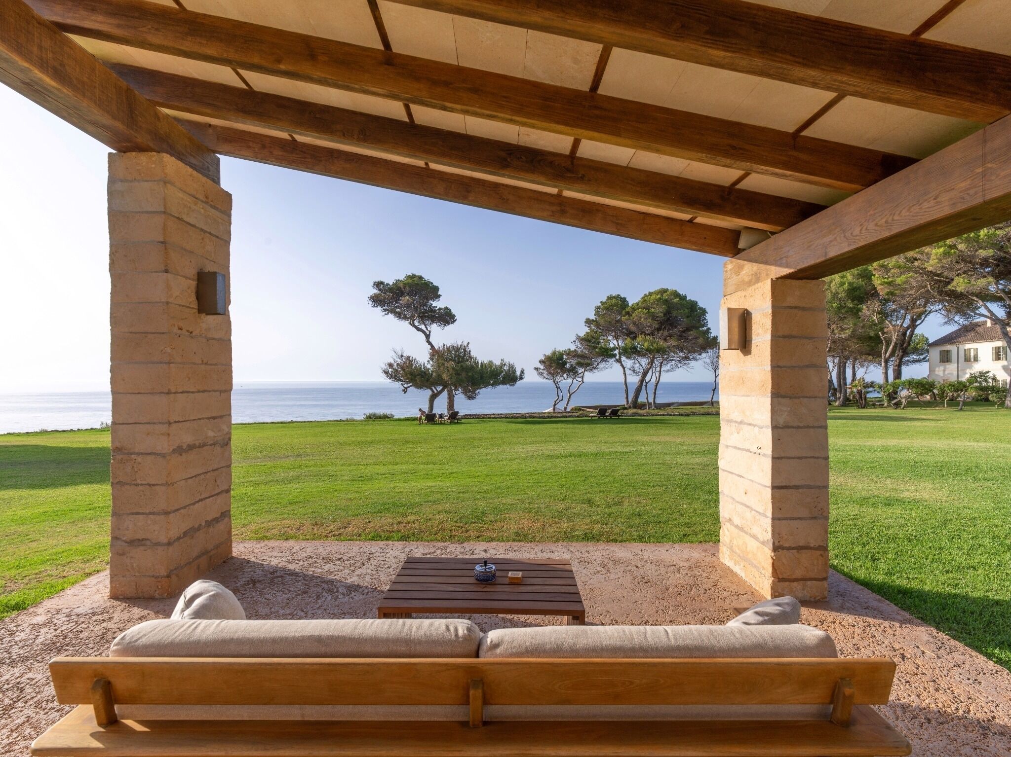 Un espacio de estar al aire libre, cubierto, con vista al mar y a los árboles.
