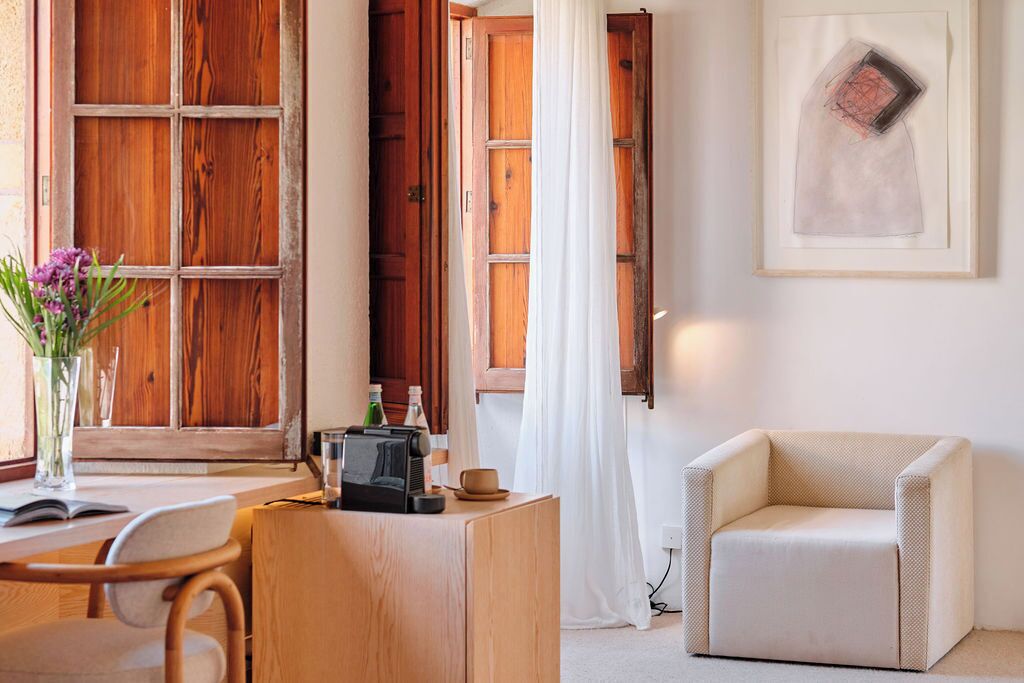 A cozy room with wooden doors, a white curtain, a framed artwork, a small table with a radio, and a beige armchair.