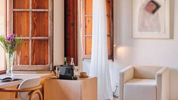 A cozy room with wooden doors, a white curtain, a framed artwork, a small table with a radio, and a beige armchair.