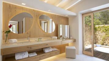A modern bathroom with a wooden vanity, dual mirrors, and a large window offering a view of a garden.
