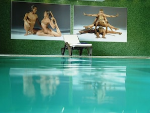 A swimming pool with a lounge chair and two large posters on the wall. - Vila Gale Collection Douro Hotel (Lamego)