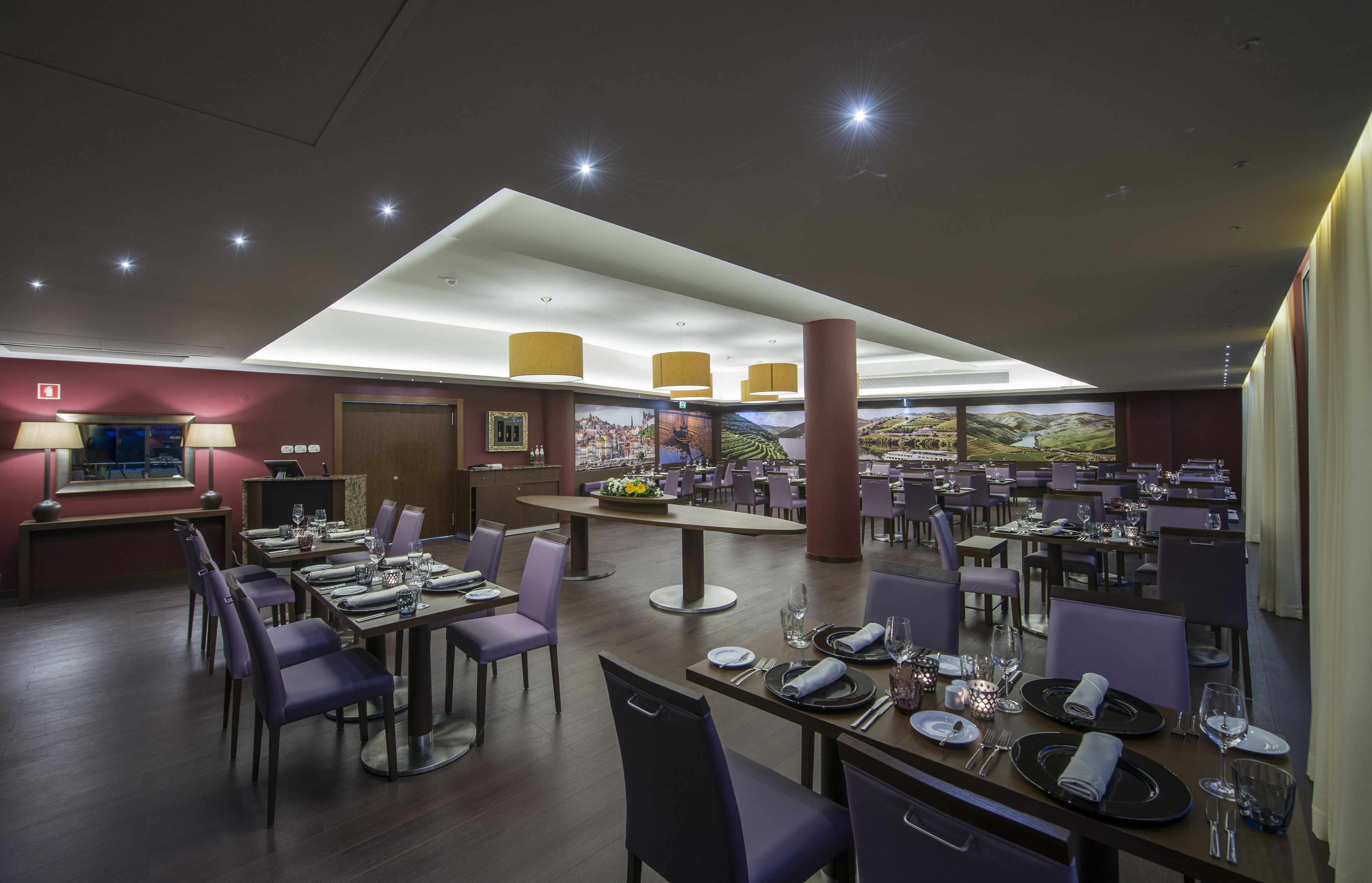 Een ruim restaurant met verschillende eetgedeeltes, paarse stoelen en gedekte tafels voor gasten.