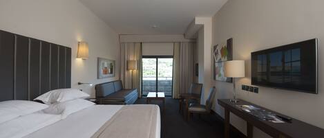 A hotel room with a large bed, a desk, a chair, a TV, and a balcony with curtains.