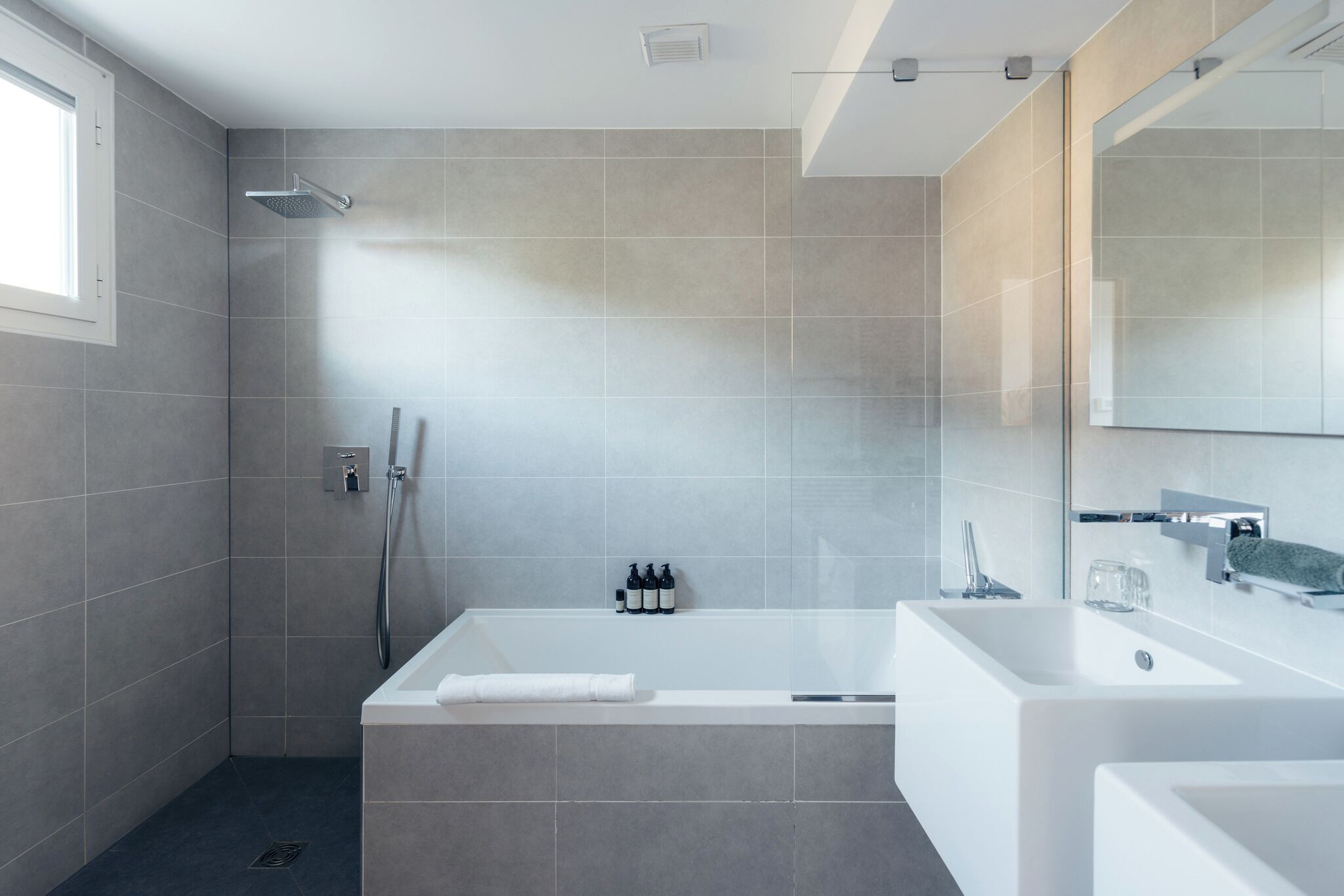 A modern bathroom with a walk-in shower, a freestanding bathtub, and a large mirror.