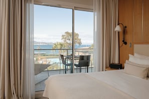 A hotel room with a bed, a nightstand, a lamp, a view of the sea, and a balcony with a table and chairs. - Kube Hotel Saint-Tropez (Gassin)