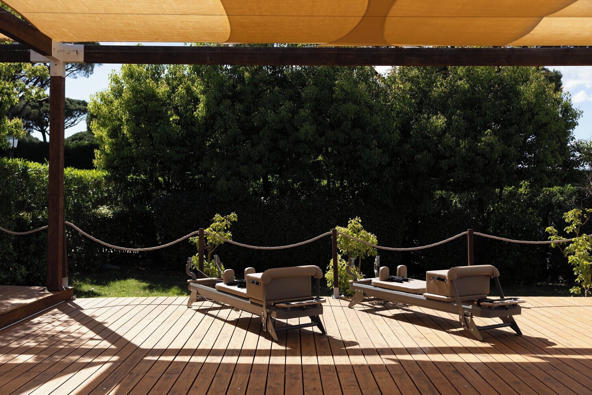 Une terrasse extérieure avec deux chaises longues, un auvent au-dessus et une barrière en corde.