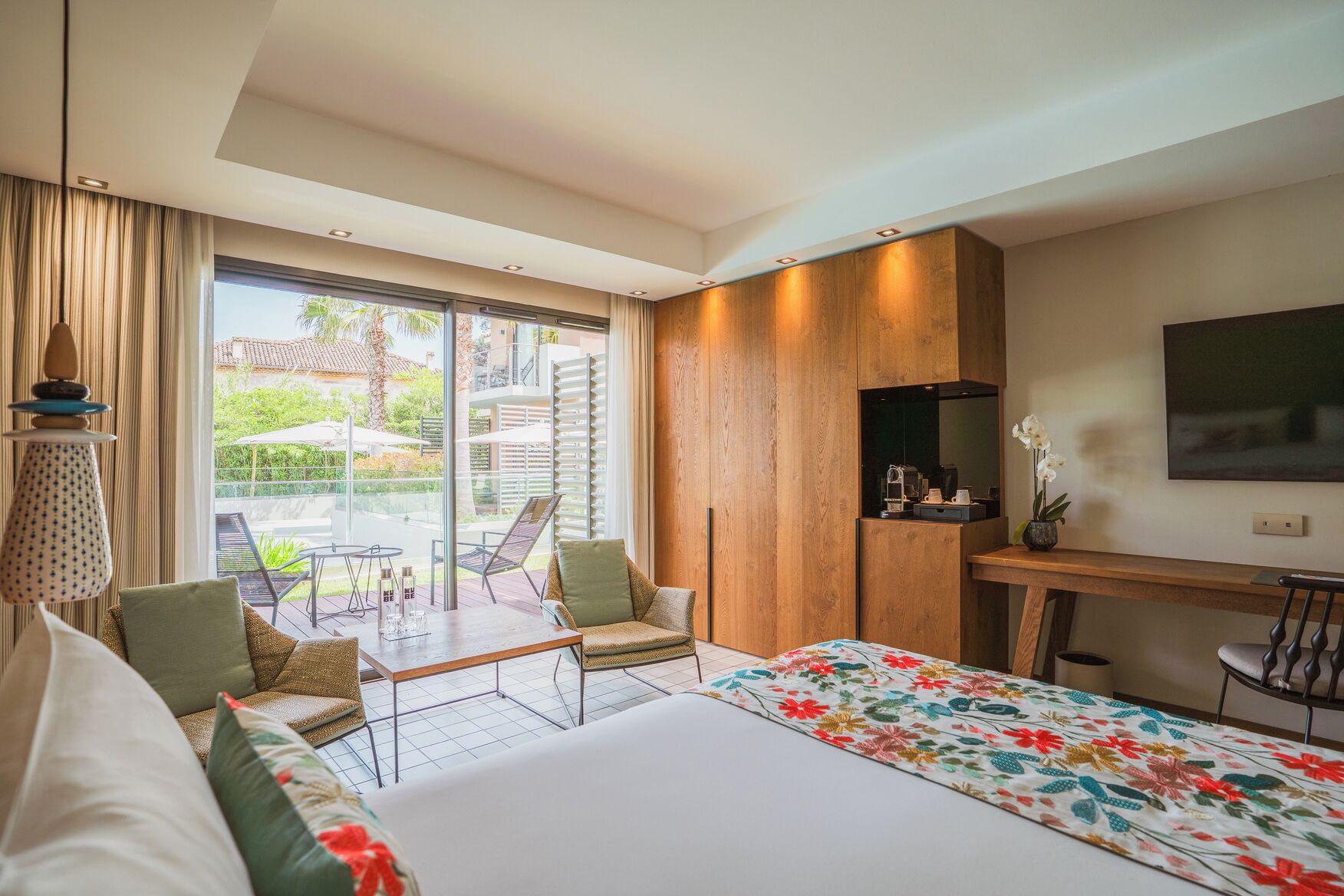Une chambre d’hôtel moderne dotée d’un grand lit, d’un bureau, d’une télévision et d’un balcon avec des sièges d’extérieur.