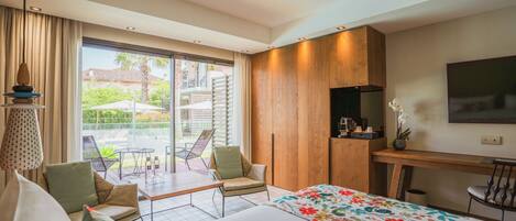 Une chambre d’hôtel moderne dotée d’un grand lit, d’un bureau, d’une télévision et d’un balcon avec des sièges d’extérieur.
