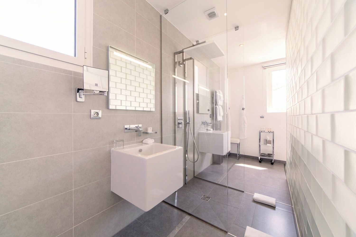 Un bagno moderno con box doccia in vetro, lavandino bianco e specchio.