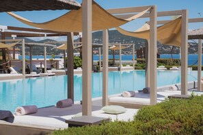 Un espace piscine doté de chaises longues et de parasols, offrant une vue sur un paysage côtier.