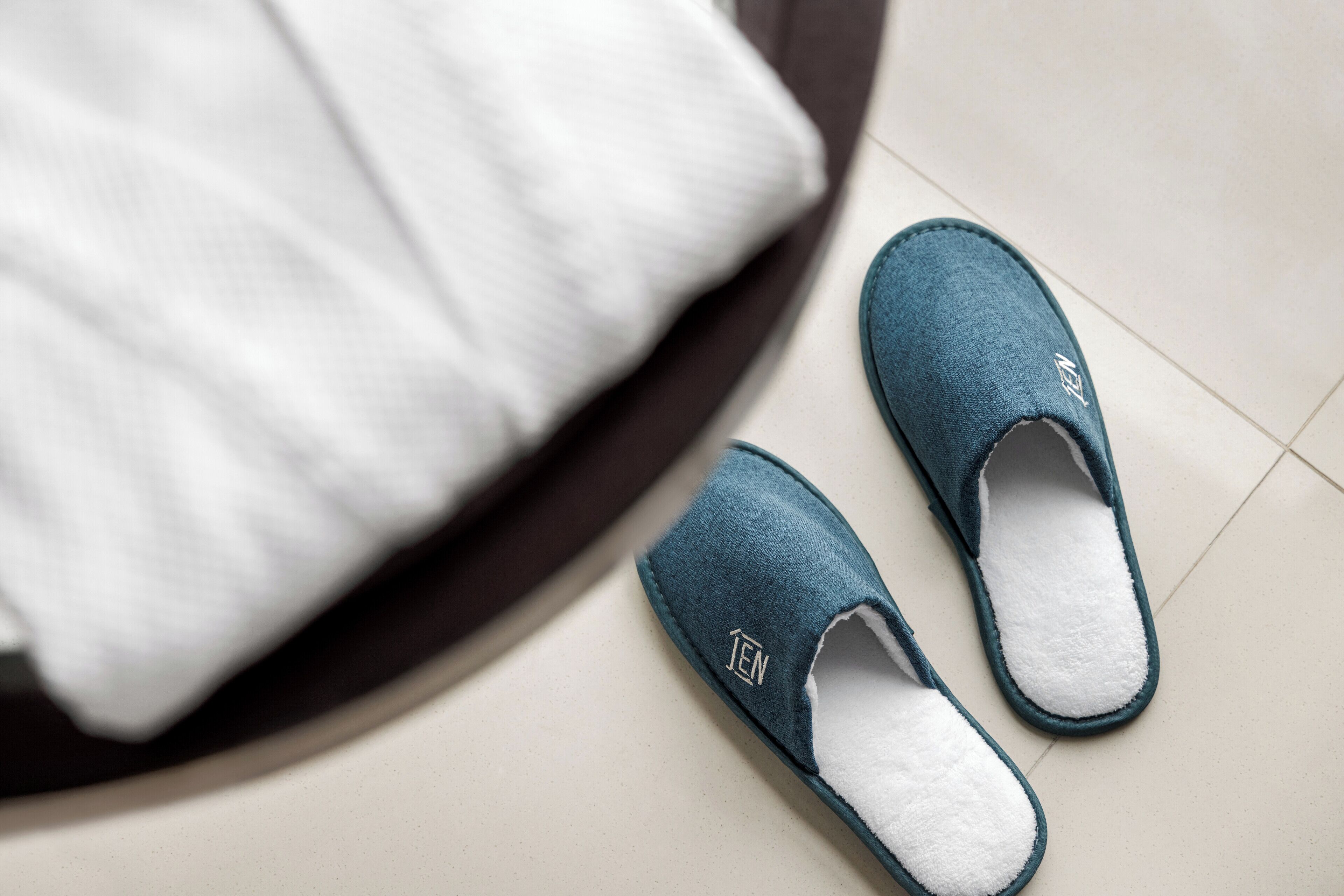 A pair of blue slippers with a white logo on a tiled floor.