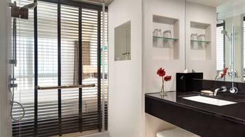 A modern bathroom with a glass-enclosed shower, a black countertop sink, and a large mirror.
