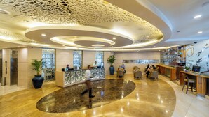 A modern hotel lobby with a reception desk, seating area, and a bar. - JEN Maldives Male by Shangri-La (Malé)