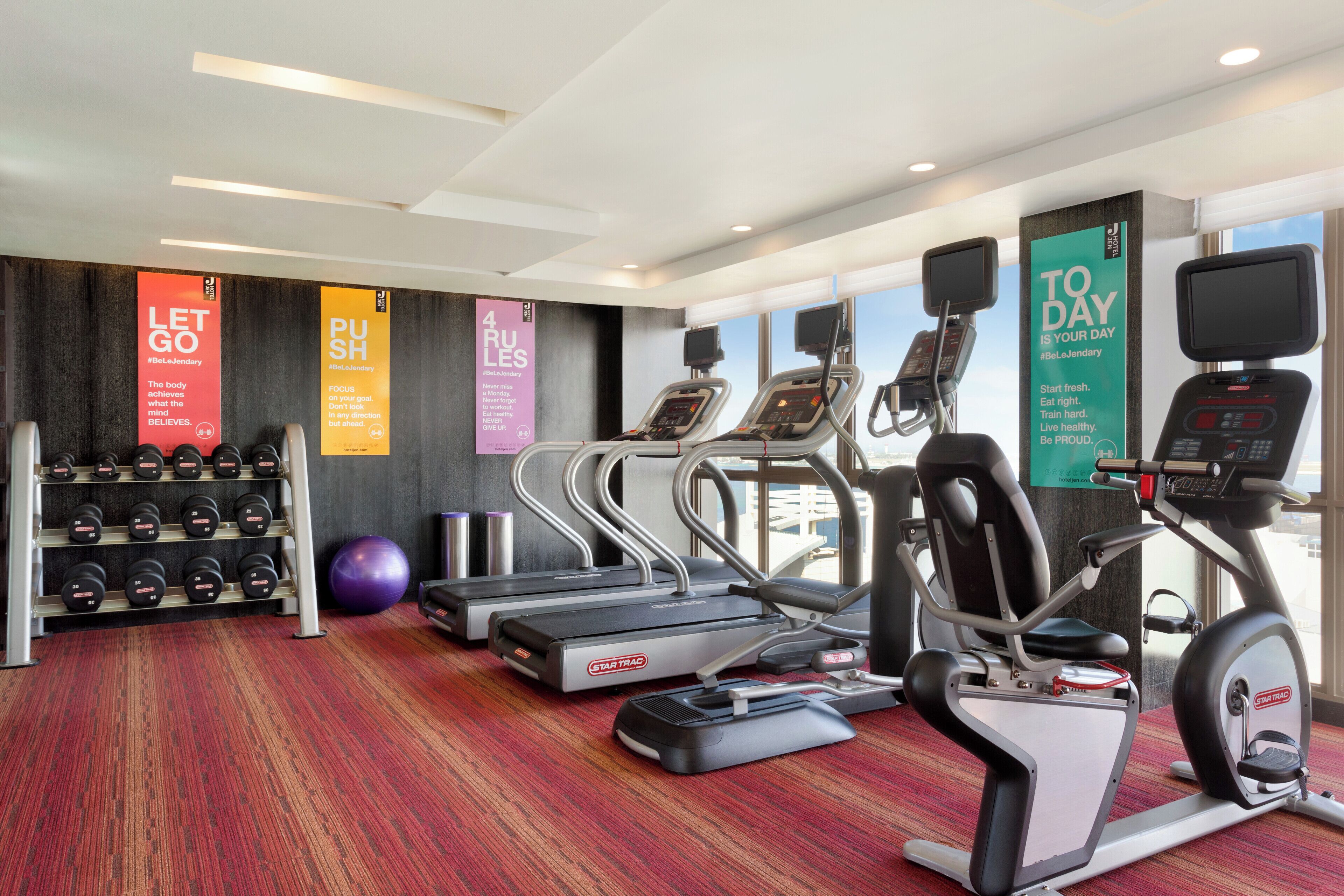 Ein Fitnessstudio mit Laufbändern, Crosstrainern und Kurzhanteln.