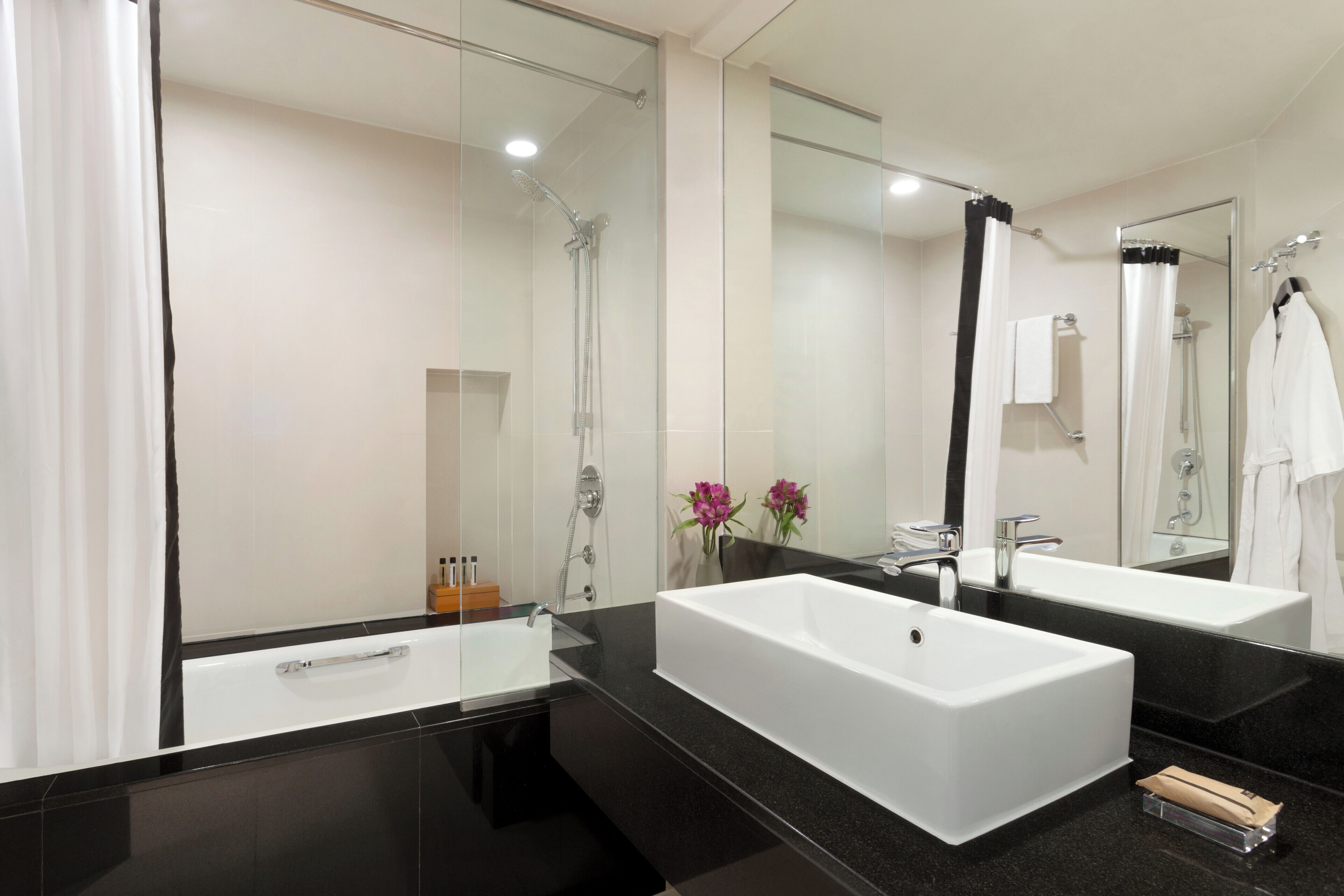 Un baño moderno con dos lavamanos grandes de color blanco, una cabina de ducha con paredes de vidrio y un espejo amplio.