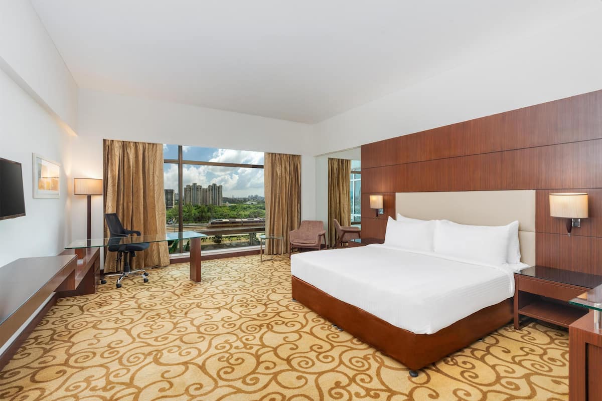 A hotel room with a large bed, a desk, a chair, and a TV.
