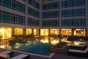 Una piscina al aire libre, sillones reclinables de piscina