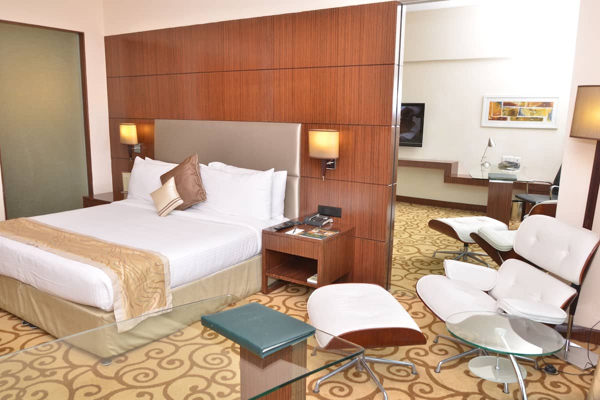 A hotel room with a bed, bedside tables, a desk, a chair, and a mirror.