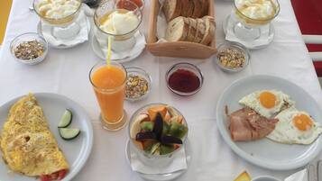 Una mesa de desayuno con diversos platos que incluyen huevos, tostadas, fruta y bebidas.