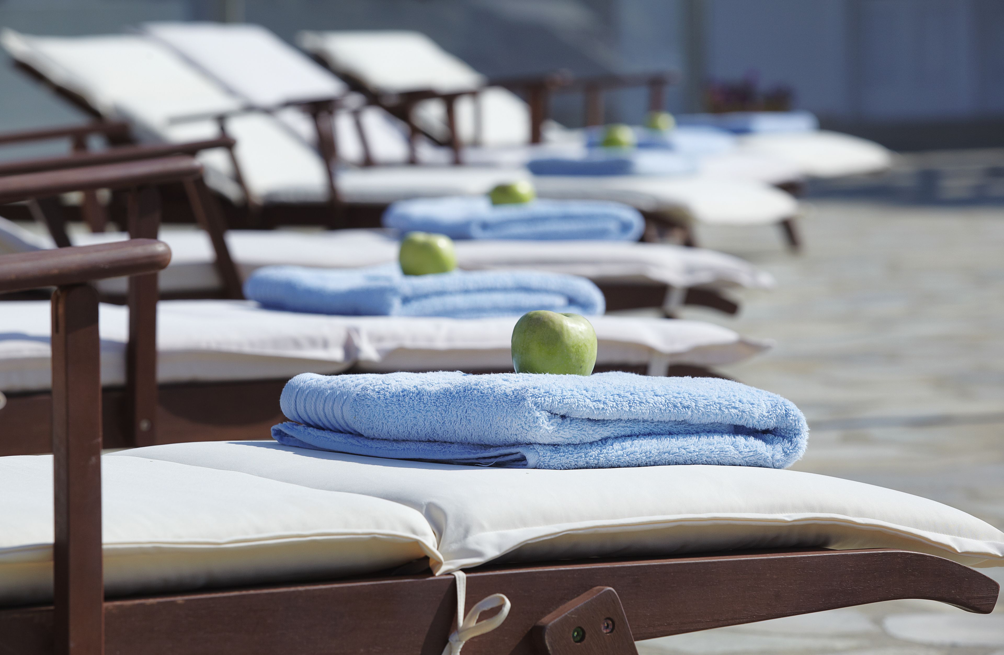 A row of sunbeds with towels and apples, suggesting a spa or relaxation area.