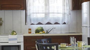 A kitchen with wooden cabinets, a white stove, a glass table, and a black chair.