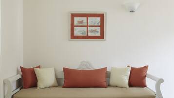 A white sofa with a beige cushion and four pillows in red and white.