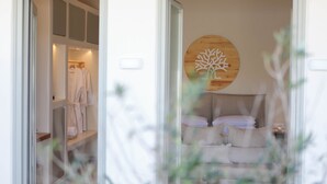 A bedroom with a bed, pillows, and a wooden wall decor. - Kedros Villas (Naxos)