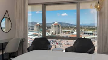 Ein Hotelzimmer mit großem Fenster und Blick auf die Stadt, einschließlich Gebäude und Berge.