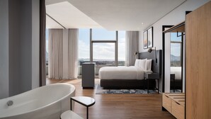 Une chambre à coucher moderne avec une grande fenêtre, une baignoire, un lit et une armoire en bois.