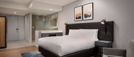 A modern bedroom with a large bed, bedside tables, a chair, and a desk with a mirror.