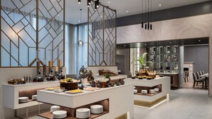Un hall d’hôtel moderne doté d’un espace buffet central, de différents types de sièges et d’un mur décoratif orné de motifs géométriques.