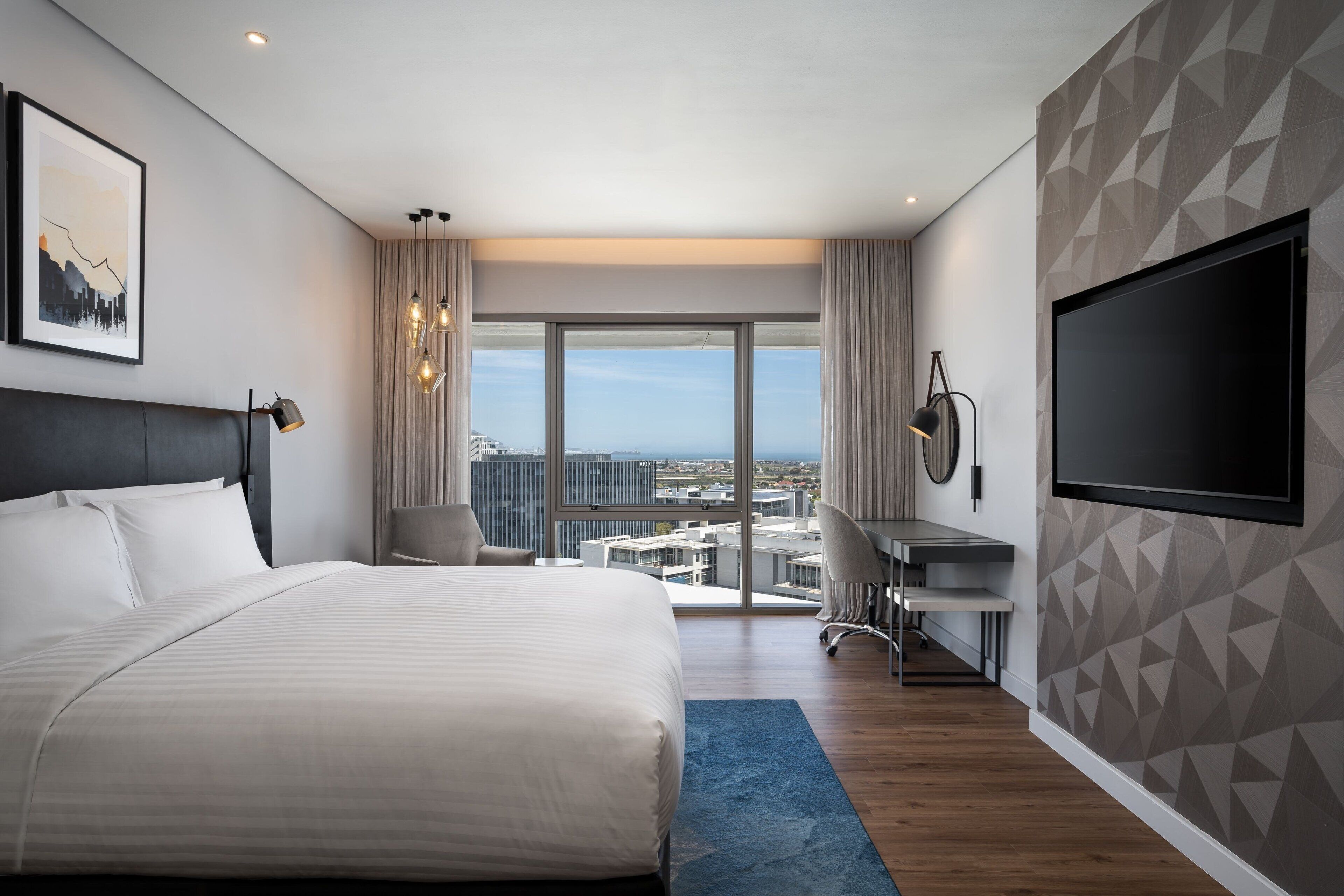 Une chambre d’hôtel moderne, dotée d’un grand lit, d’un bureau, d’une chaise et d’un téléviseur.
