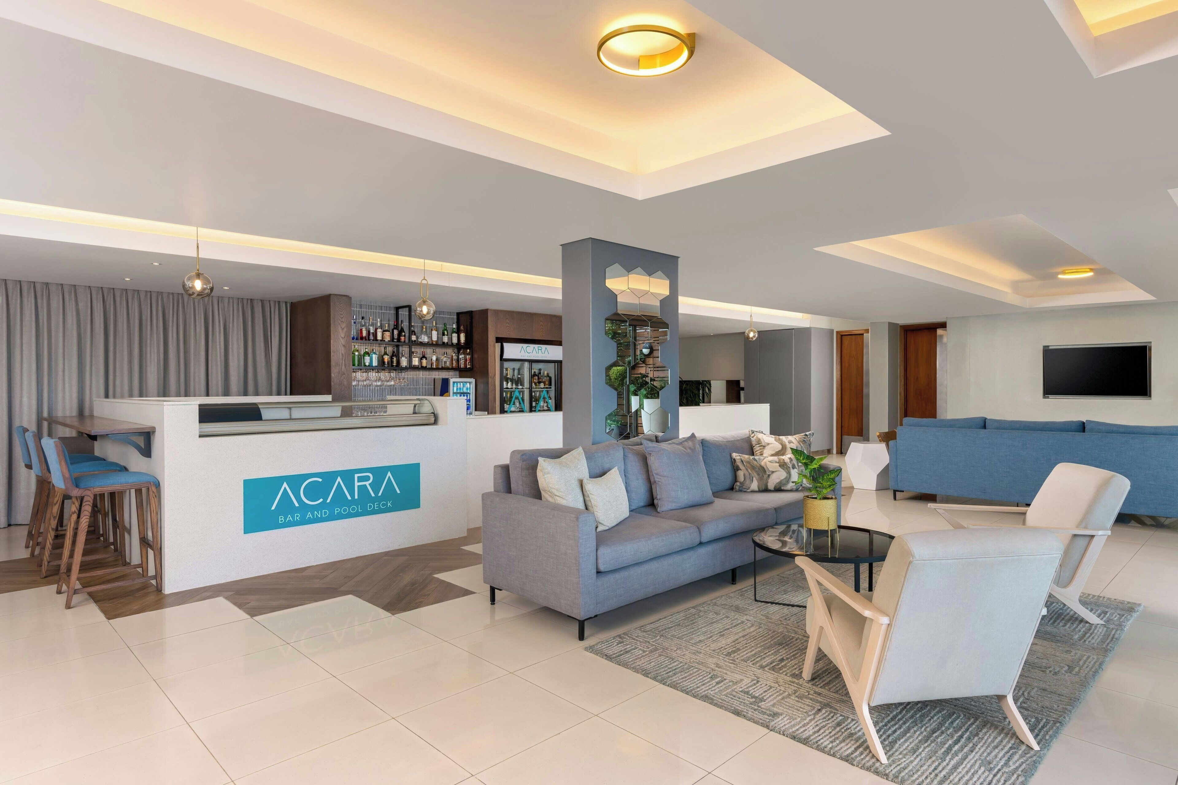 Un espace de vie moderne comprenant un bar, des sièges et un panneau indiquant l’accès à la piscine.