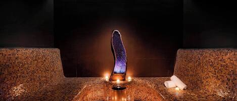 A mosaic-tiled bench with a central pillar and candles.