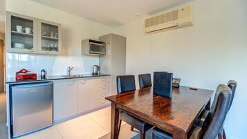 A modern kitchen with a built-in microwave, a refrigerator, and a dining area with a wooden table and chairs.