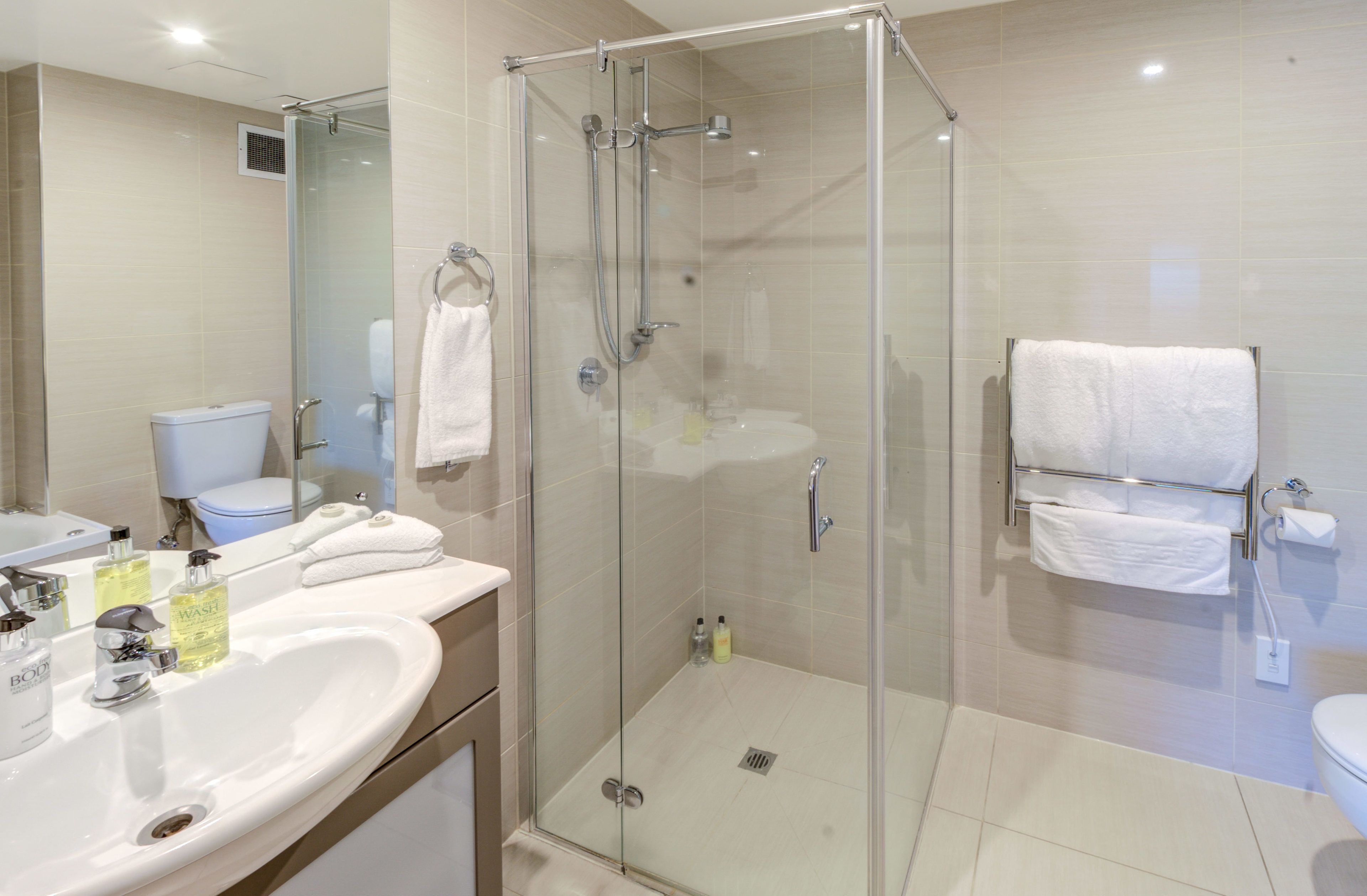 Un bagno moderno con doccia vetrata, lavabo con articoli da toilette e WC.