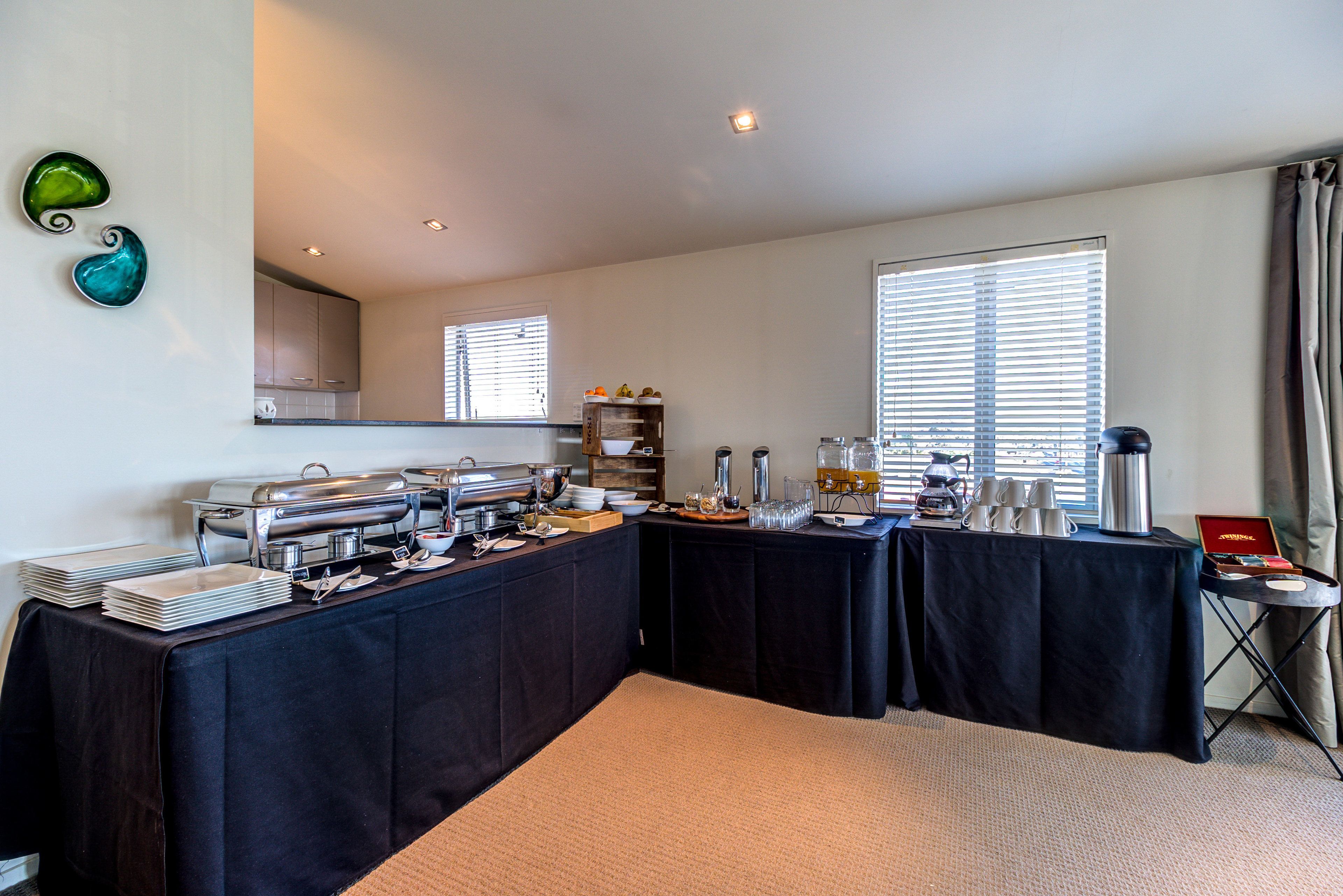 A buffet setup with multiple tables, a coffee station, and a small seating area with a table and chairs.