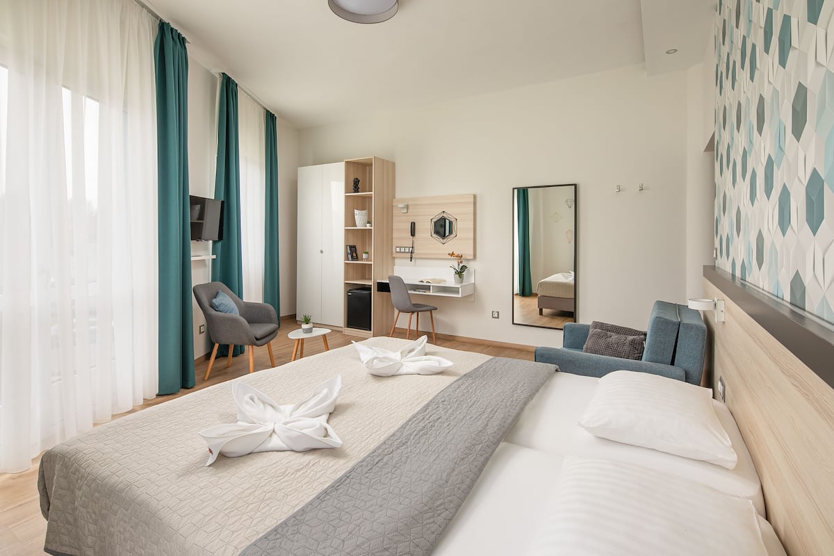 A hotel room with a bed, a desk, a chair, a wardrobe, and a mirror.