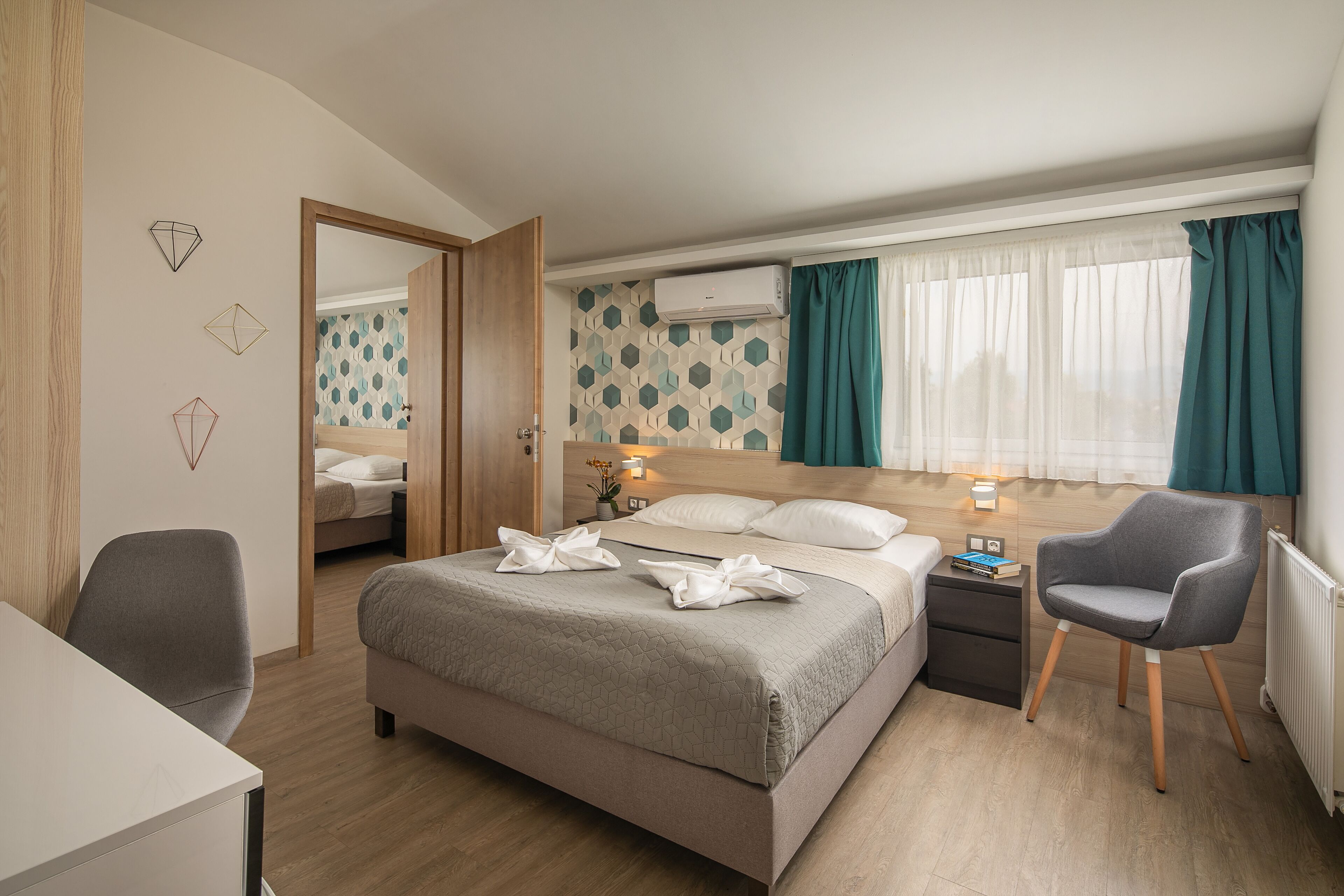 Una habitación de hotel moderna con cama, escritorio, silla y mesita de noche.