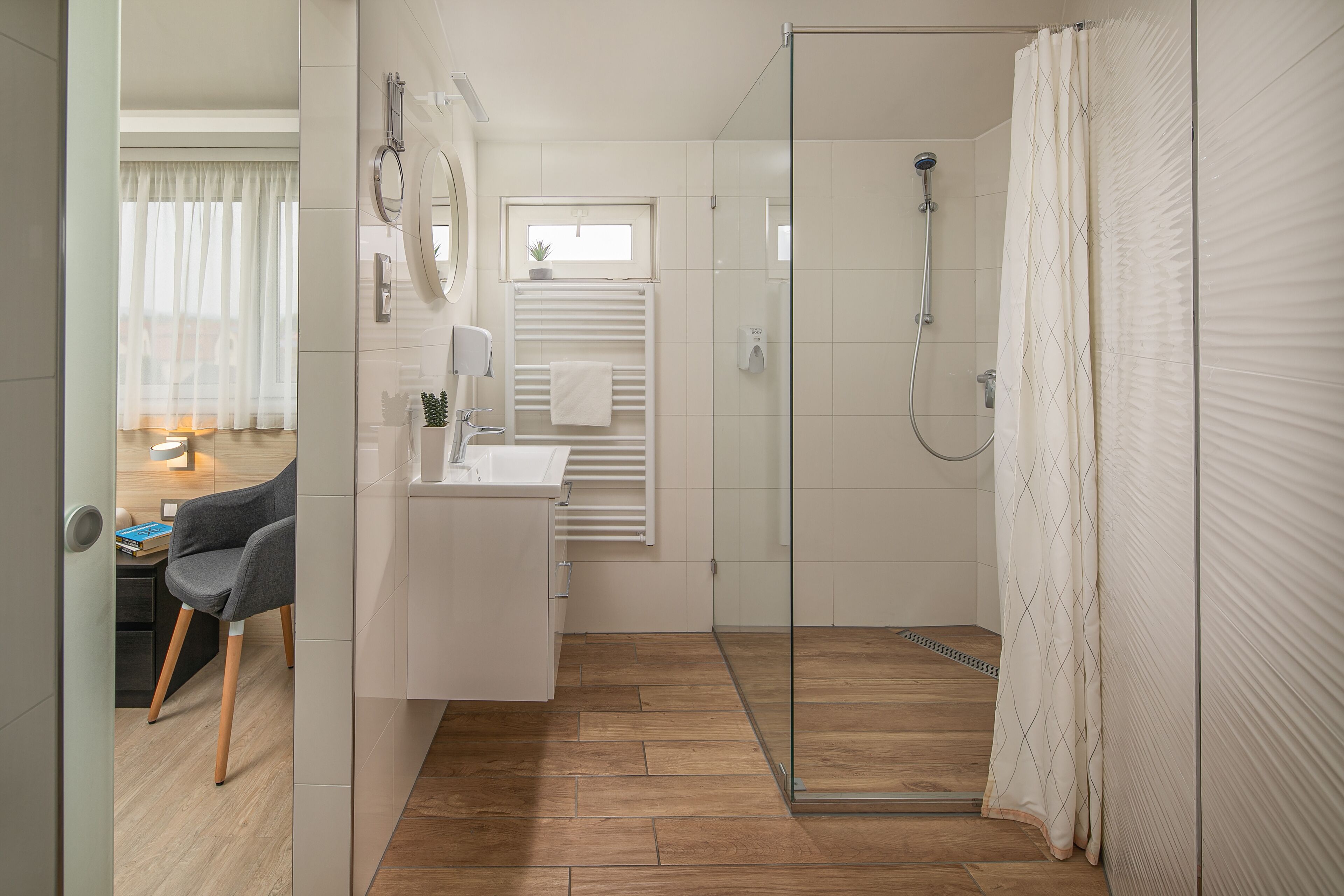 Une salle de bain moderne avec une douche à parois de verre, un lavabo blanc et un porte-serviettes.
