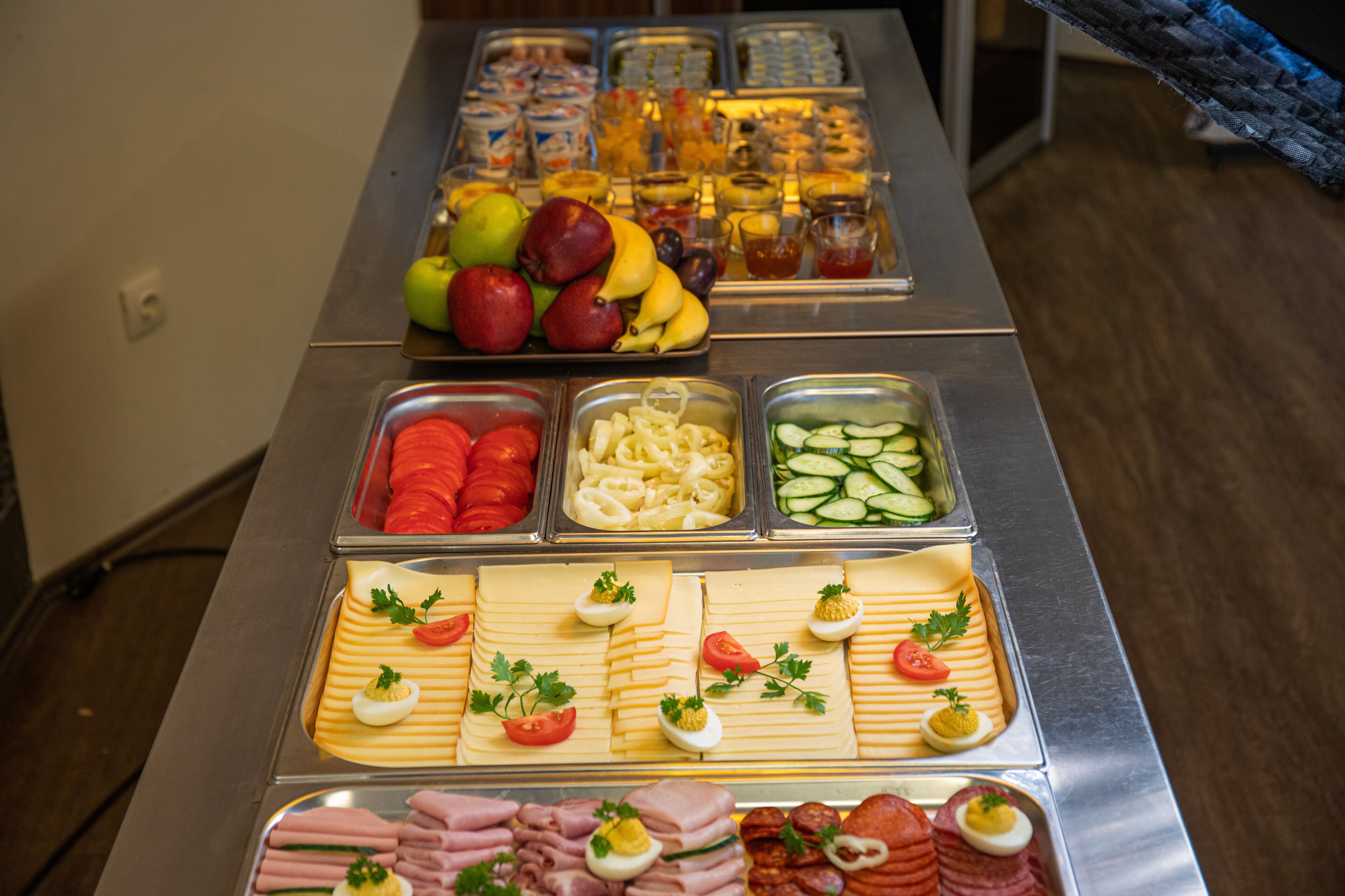 A buffet with various food items including fruits, vegetables, cheeses, meats, and eggs.