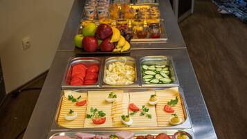A buffet with various food items including fruits, vegetables, cheeses, meats, and eggs.