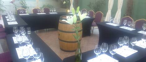 A restaurant with tables set for dining, featuring a central decorative wooden barrel and a vase with flowers.