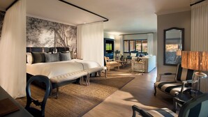 Ein modernes Hotelzimmer mit einem großen Bett, einem Schreibtisch, einem Sessel, einer Couch und einem Essbereich.