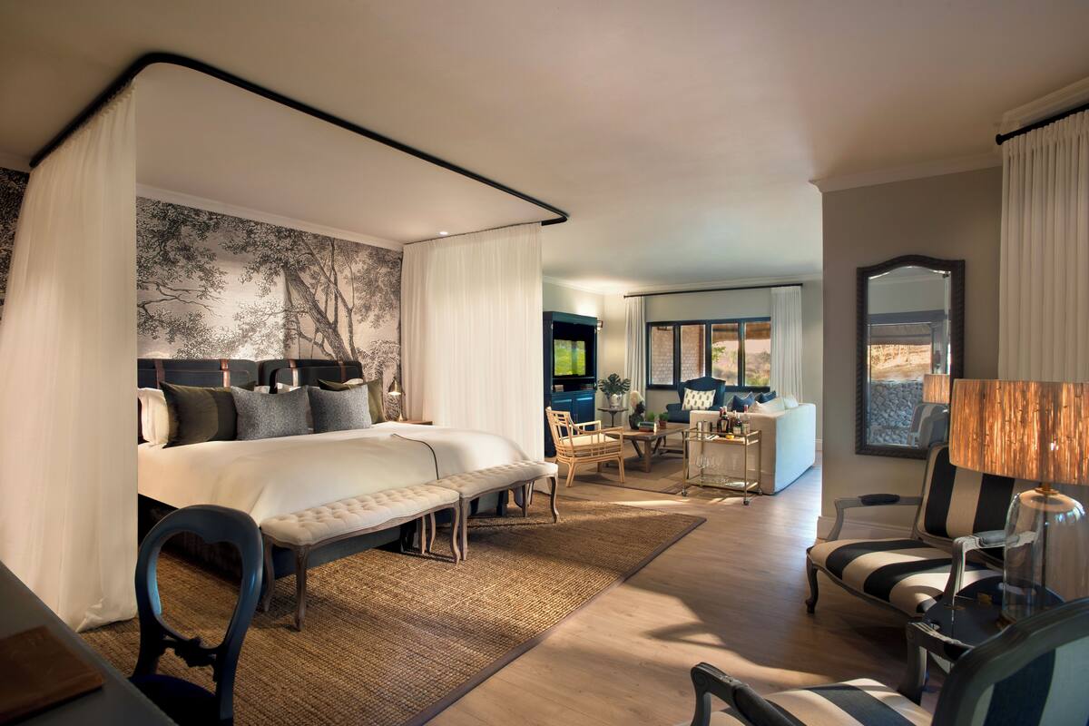 Ett modernt hotellrum med en stor säng, ett skrivbord, en stol, en soffa och en matplats.