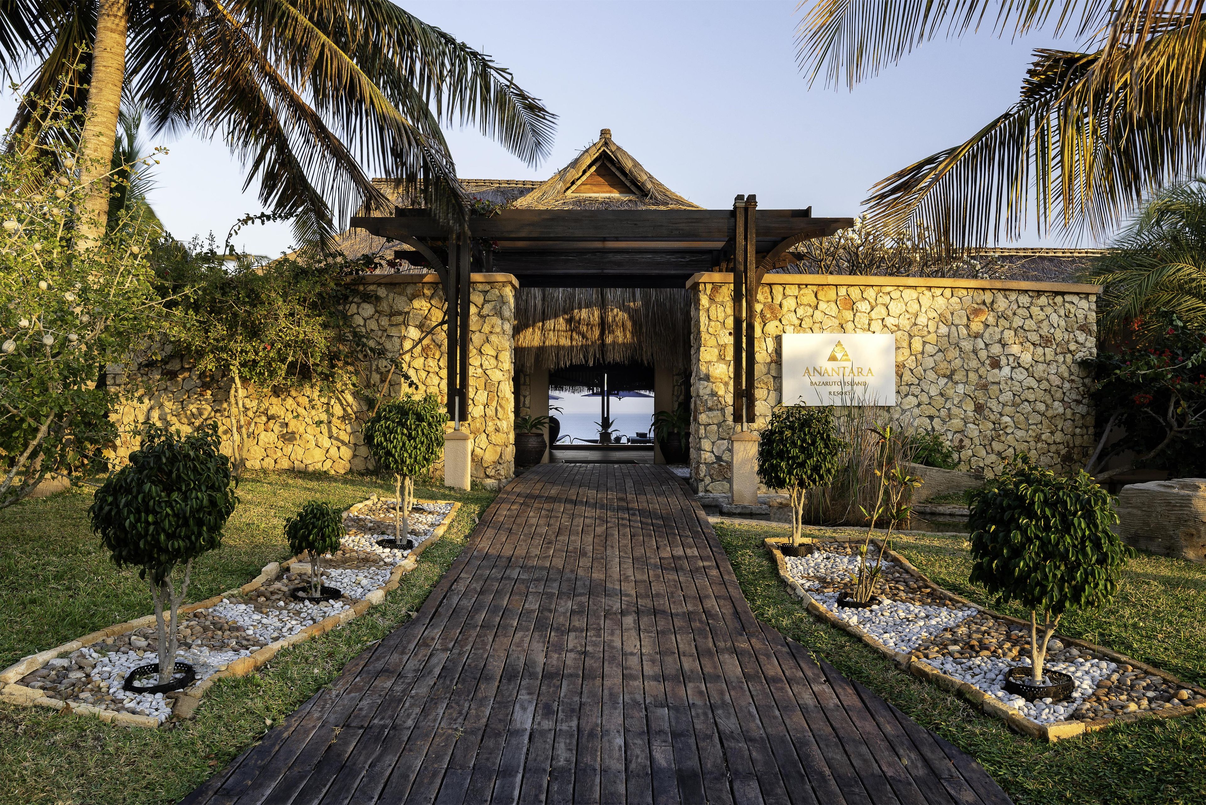 A stone building with a wooden entrance archway, a signboard, and a pathway leading to a beach.