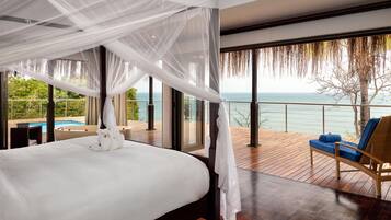 Un dormitorio con cama a dosel, vista al mar y terraza de madera con una silla.