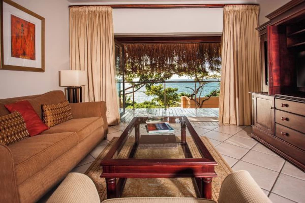 Una sala de estar con sofá, mesa de centro y vista al mar.