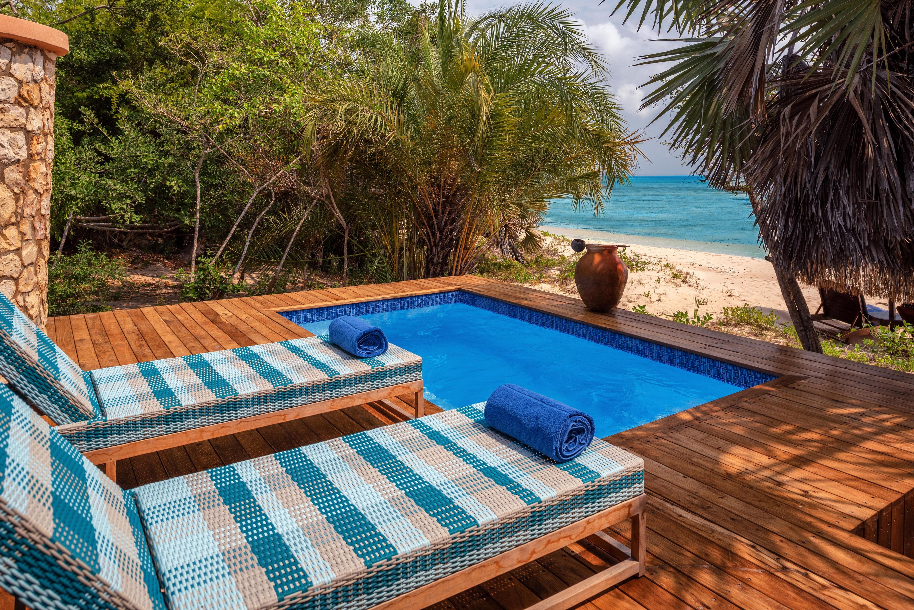 Eine Holzterrasse mit zwei Liegestühlen und einem kleinen Pool.