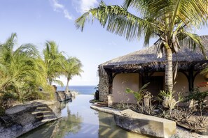 Un resort tropical con piscina, palmeras y vista al océano.